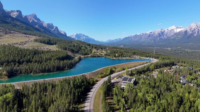 Canmore Rundle Forebay and Highway 742 Spray Lakes Road through autumn pine forest and mountains aerial view. Canmore, Alberta, Canada.