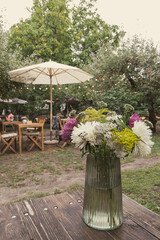 Wildflower bouquet in glass vase on wooden table in outdoor cafe © emerald17