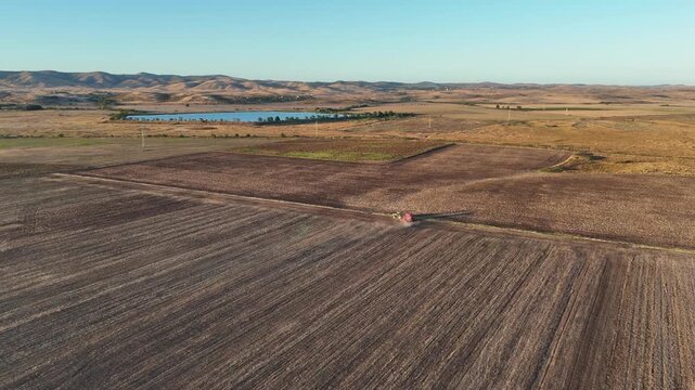 High angle aerial shot of a tractor turning on the edge of a field to plow the next row