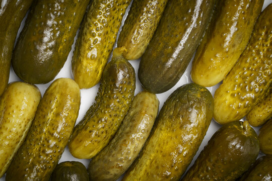 Dill pickles arranged in two rows with white background