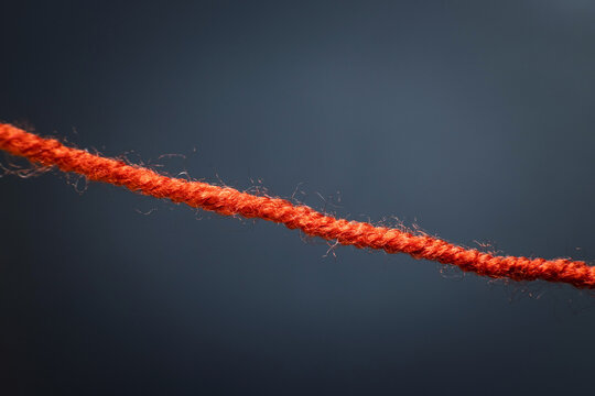 Thin red rope laid flat against a dark background, decorative or utility rope
