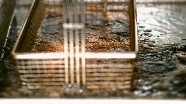 Close-up of rusty industrial drain grate with wet bubbling water, muddy grime, and warm amber reflections on corroded metal rails in industrial workshop