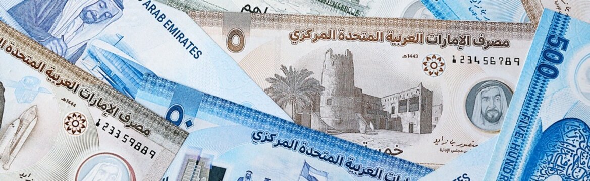 UAE dirham money bills in pile on table. United Arab Emirates AED currency cash close up