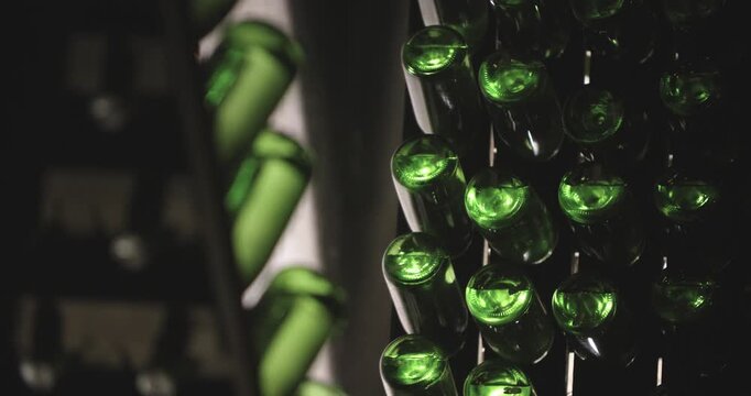 Closeup of working hands with bottles. Top down view of workers handling glass bottles carefully. Precise placement of dark glass bottles by gloved hands in cellar storage