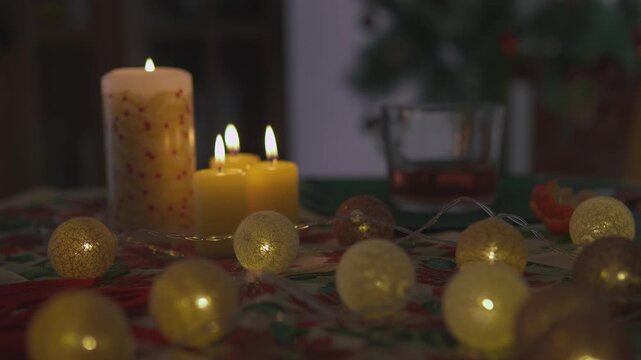 Close footage shows female hands that hold a transparent glass of red holiday punch near glowing candles. Close cinematic view highlights festive beverage presentation through warm seasonal detail.
