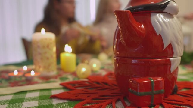 Seasonal lifestyle footage shows a red Santa mug surrounded by glowing candles and soft holiday bokeh. Cinematic close view conveys cozy Christmas atmosphere in a polished lifestyle scene.
