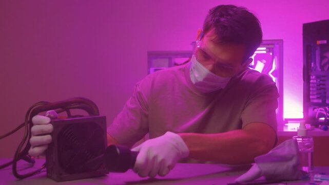 Technician cleaning computer. Expert cleaning and examining computer hardware meticulously. Technician carefully clearing dust from open computer with specialized tools