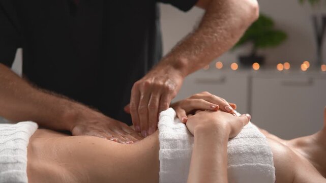 A client relaxes as a massage therapist covers and relaxes the eye area with slow symmetrical hand movements. This treatment shows eye strain relief, deep relaxation and wellness practice.