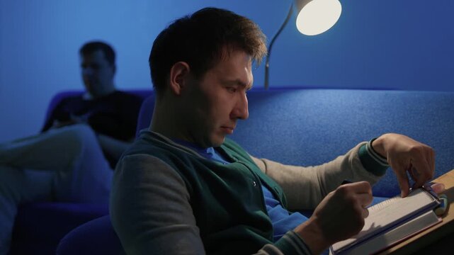 Individual concentrates while reviewing documents quietly. Lone individual carefully examines handwritten notes under gentle illumination during late night hours at home