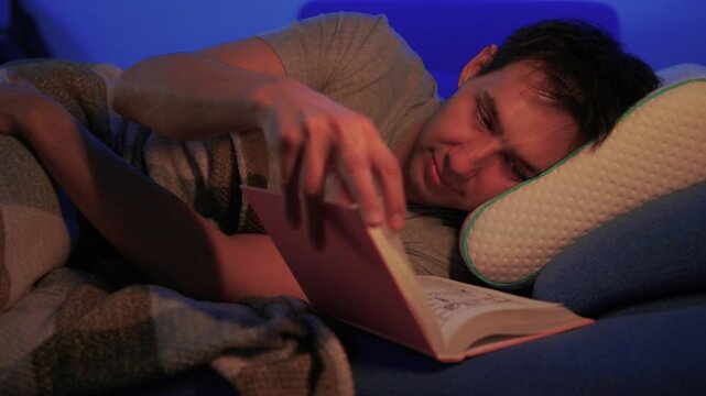 Peaceful reading night. Serene evening features soft illumination and relaxing book time for man. Quiet night envelops man in cozy atmosphere as he peacefully enjoys reading
