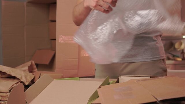 Person organizes books for shipment. Individual carefully prepares books for dispatching. Person methodically stacks and secures books inside boxes for mailing process
