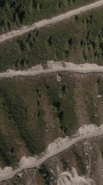 Drone footage of the steep zigzag dirt road descending Katu-Yaryk Pass into Chulyshman Valley, Altai Republic, Russia, dramatic mountain landscape