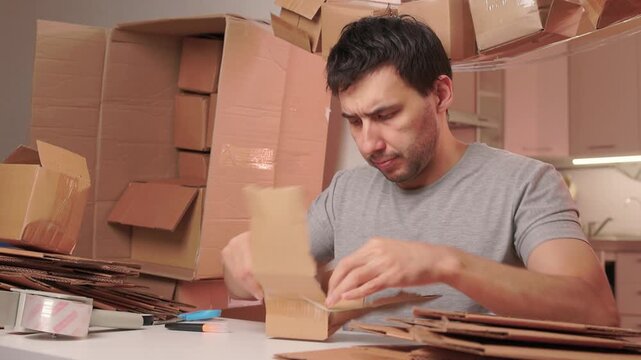 Man packs swiftly. Worker rapidly assembling and sealing packages at busy station. Energetic individual quickly folding and locking tabs on cardboard boxes for shipping