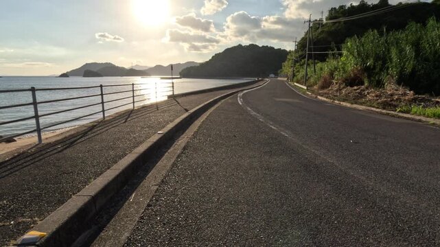 Evening glare on the sea beside an empty island road