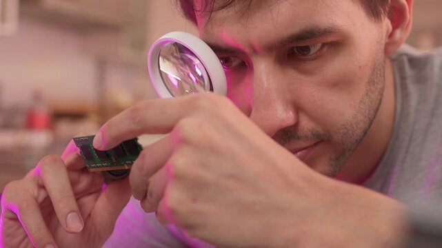 Scientist analyzes prototype circuit in creative workspace atmosphere. Innovator carefully tests experimental electronic device amidst vibrant studio setting with tools