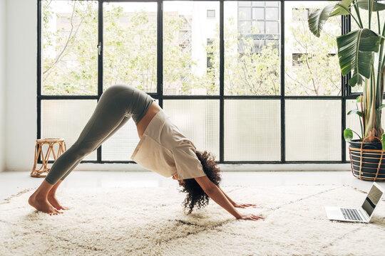 Woman doing downward dog yoga pose at home