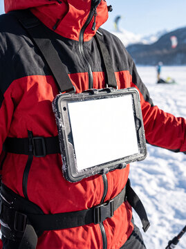 tablet with blank white screen mounted on a chest harness over a red jacket in winter mountains showing convenient technology use during active outdoor sports