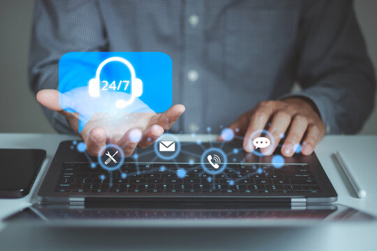 Businessman using a laptop with a 24/7 customer support icon, illustrating digital communication, technical assistance, online service, live chat, email, phone contact and business connectivity.
