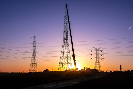 Crane Erecting Steel Transmission Tower Near Power Lines