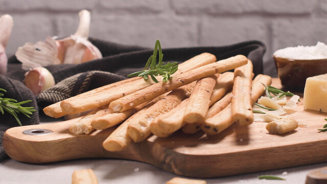 Grissini bread sticks on a wooden board with garlic and cheese