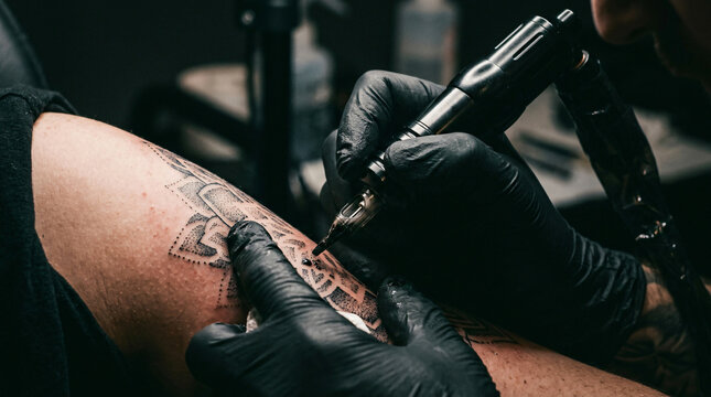 Extreme close up macro shot tattoo artist black sterile glove holding professional rotary machine gun ink layering intricate detailed design clients skin arm shoulder layout