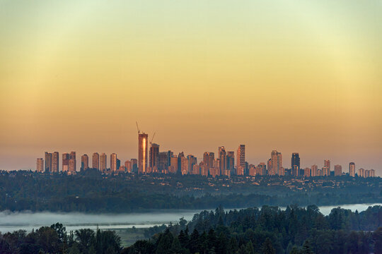 Golden hour city skyline with a construction crane and fog