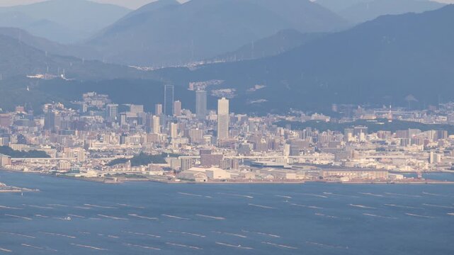 Hiroshima City aerial panoramic view seen from Mount Misen on Miyajima Island, with Seto Inland Sea, Hiroshuma bay and skyline, port and oyster farming rafts, Chugoku, Japan, mountains in background