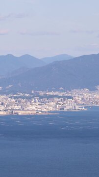 Hiroshima City aerial panoramic view seen from Mount Misen on Miyajima Island, with Seto Inland Sea, Hiroshuma bay and skyline, port and oyster farming rafts, Chugoku, Japan, mountains in background