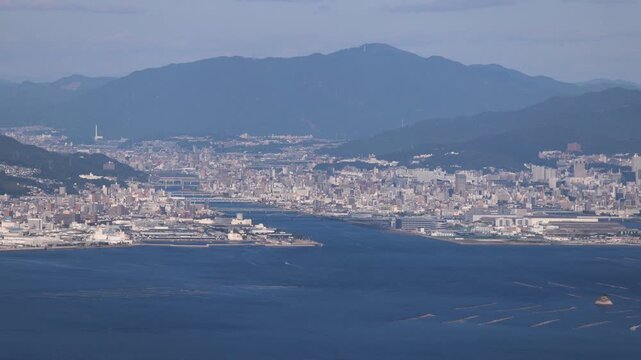 Hiroshima City aerial panoramic view seen from Mount Misen on Miyajima Island, with Seto Inland Sea, Hiroshuma bay and skyline, port and oyster farming rafts, Chugoku, Japan, mountains in background