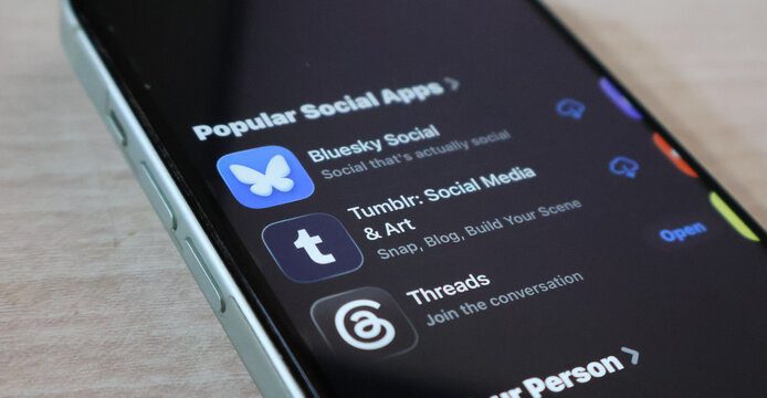 Smartphone screen displaying Bluesky Tumblr and Threads mobile application store page in dark mode.
