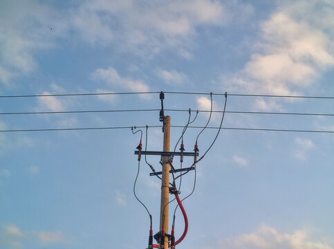 Electrical utility power pole with distribution cables under sky.