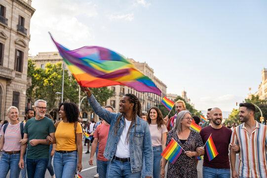 A diverse group of people marches through a city street waving rainbow flags during a pride parade to celebrate LGBTQ community visibility and social equality for all