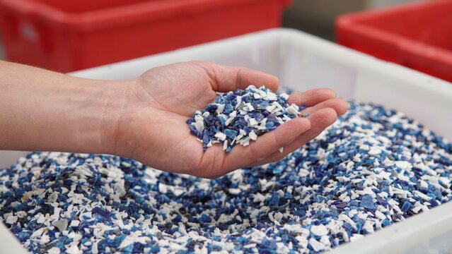 Hand holding recycled blue and white plastic