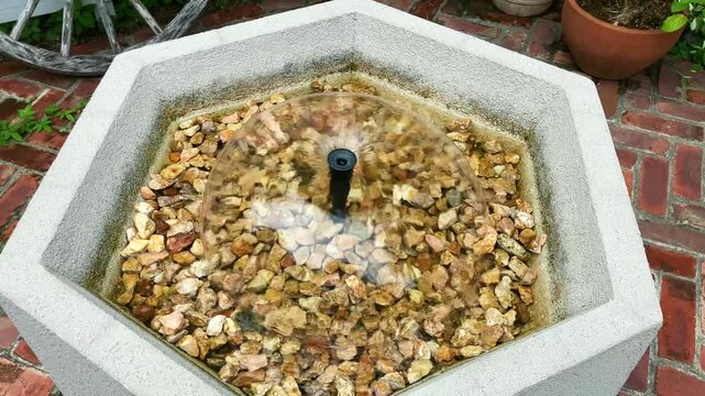 庭の六角形の水盤でドーム状に広がる噴水の水流