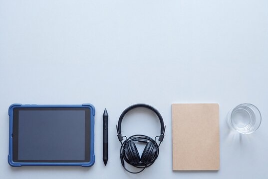 Tablet stylus headphones and notebook for online class on grey desk