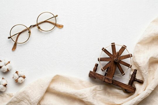 Mahatma Gandhi Jayanti tribute flat lay with round glasses charkha and khadi
