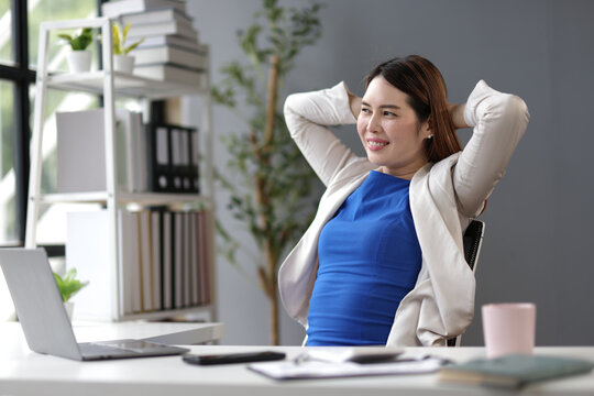 Businesswoman stretching at her desk in office.