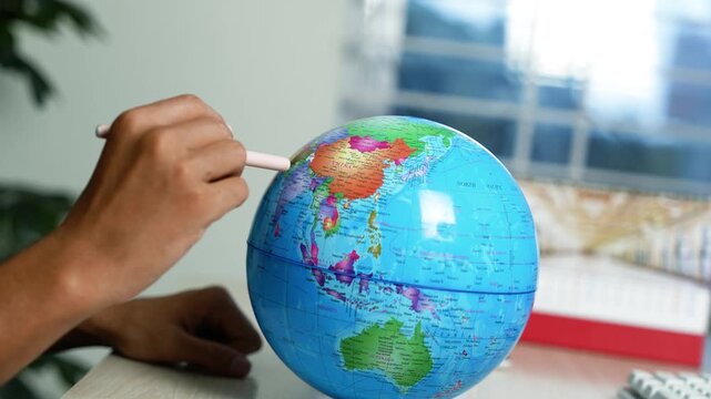 Child pointing to asia on a world globe, Child points at asia on a colorful world globe in a bright home setting, showing geography learning, travel planning and global education.