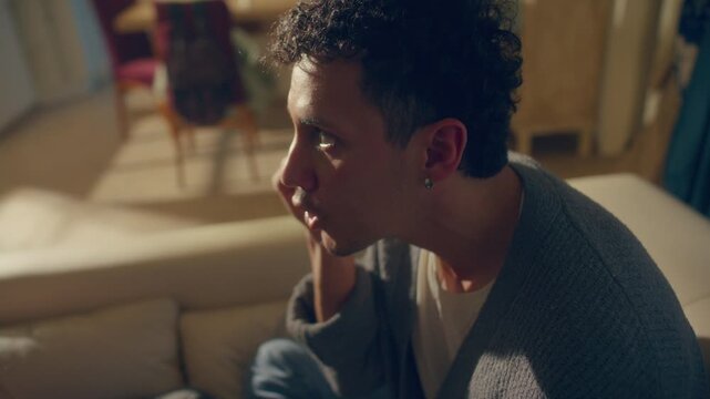 Frustrated young man and woman shouting and arguing emotionally on sofa in room bathed in golden sunlight. Close up, whip pan