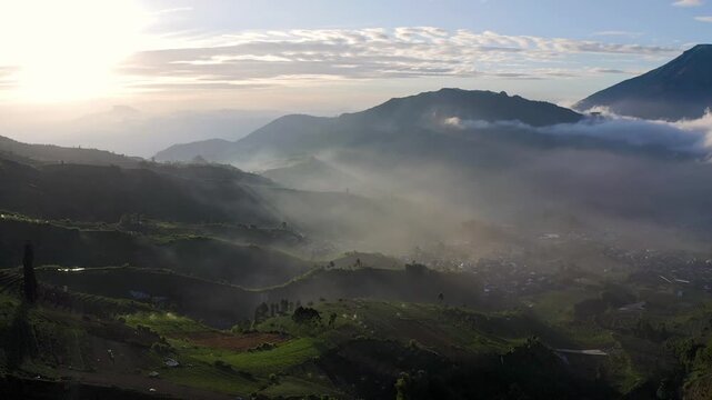 Aerial drone footage of sunrise over Mount Sindoro and misty valleys in Dieng Plateau, Central Java, Indonesia.
