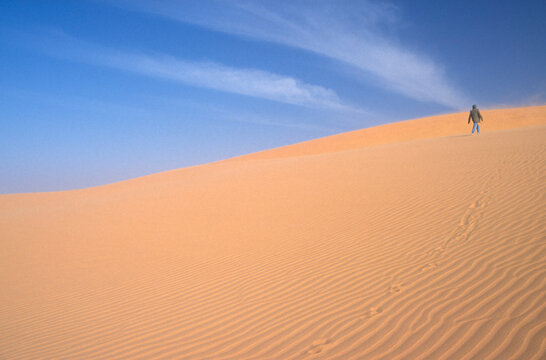 Single person walking in the Sahara Desert, concept of leaving and solitude, scanned from transparency 1989