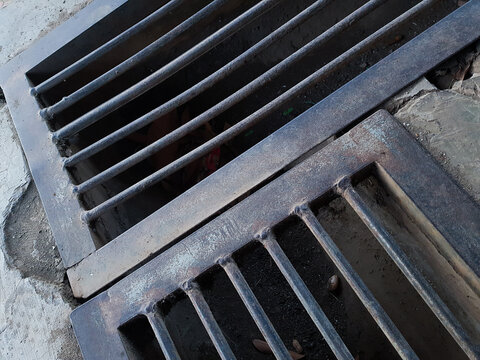 Steel drainage iron grate cover over street gutter ditch.