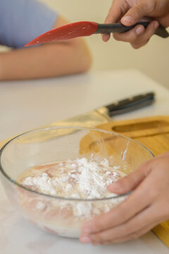 Raw minced meat being combined with ingredients in a mixing bowl during homemade recipe preparation.