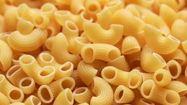 Close-up of uncooked elbow macaroni pasta pile, textured golden-yellow dry noodles for food photography and recipe styling