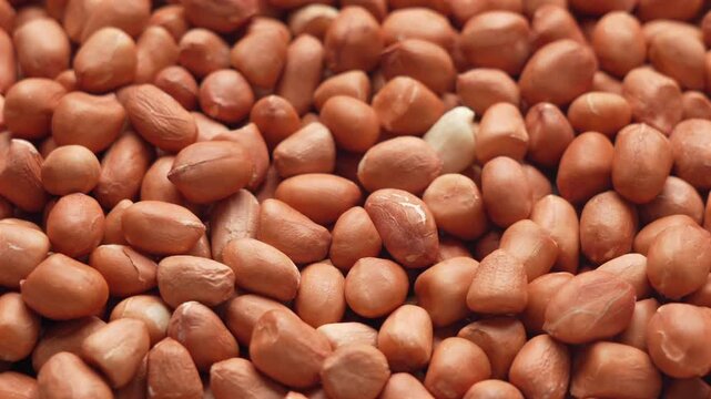 Close-up of roasted peanuts with one peeled kernel, ideal for food packaging or snack advertising