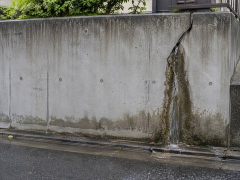 亀裂から水が流れ出る住宅地の擁壁