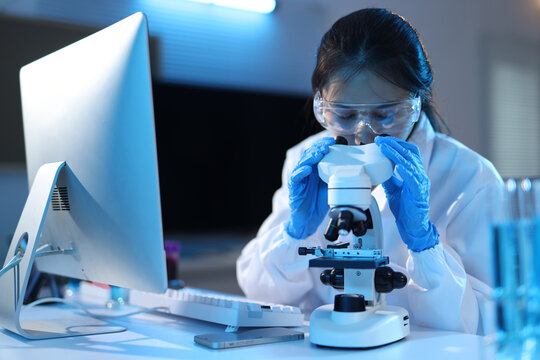 Female scientist working with microscope in laboratory research. Young woman researcher analyzing medical samples, developing new treatments or testing solutions in a modern science laboratory.