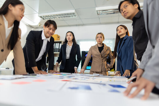 Business people collaborating on strategic planning at office meeting. Team of professionals analyzing charts and data, discussing new business strategy, working together in a modern office.