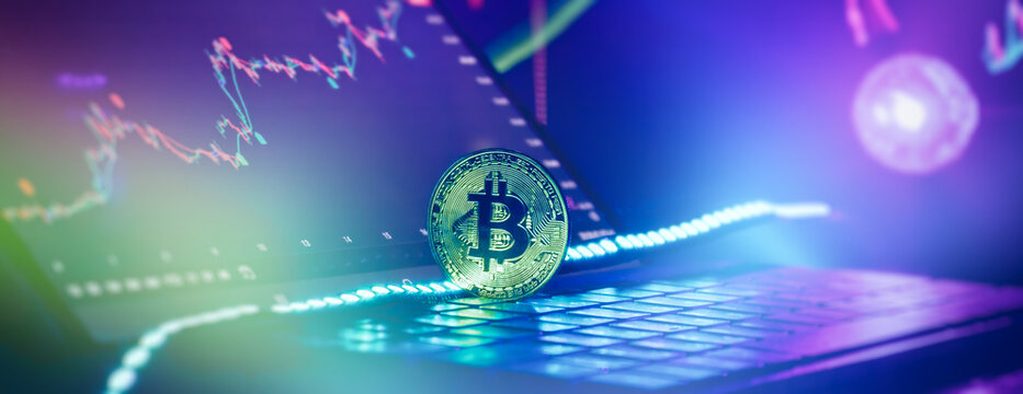Digital crypto exchange concept. Golden Bitcoin on computer keyboard against stock market graphs.