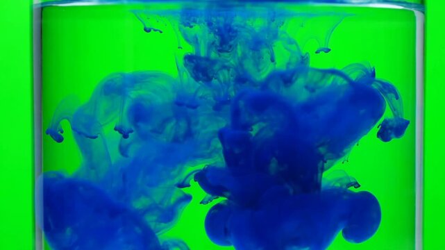 Dark blue ink drop dispersing and blooming in water on green screen